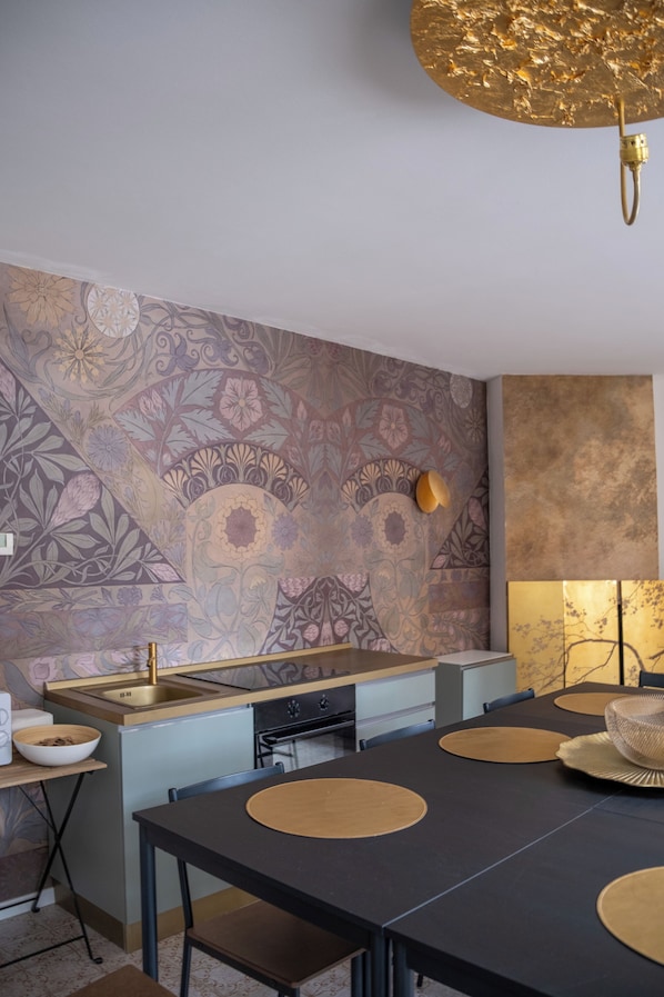 A modern kitchen with a patterned backsplash, a central island, and a dining area with a black table and gold placemats.