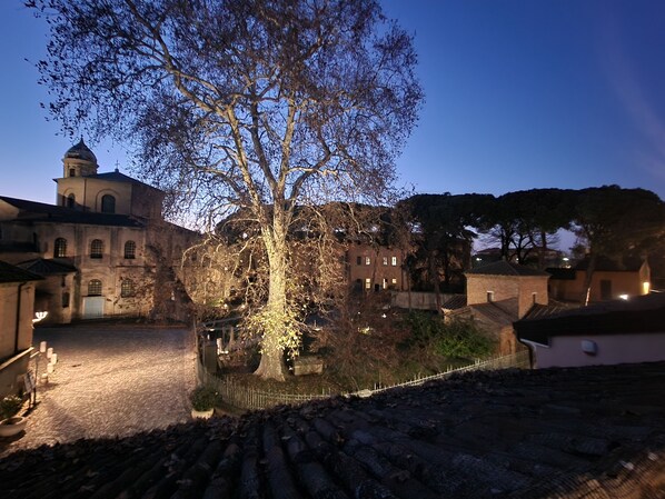 A historic building with a large tree in front, stone pavement, and a fenced area. - House 30 meters from the UNESCO monuments of San Vitale and the Galla Placidia (Ravenna)