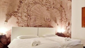 A bedroom with a large bed, a headboard, and a decorative wall mural. - House 30 meters from the UNESCO monuments of San Vitale and the Galla Placidia (Ravenna)