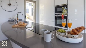 Una cocina moderna con una isla central, horno empotrado y vistas al exterior.