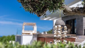 Una casa moderna con un original móvil de conchas colgando de una rama de árbol.