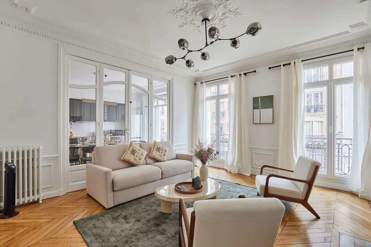 A spacious living room with a sofa, armchairs, a coffee table, and a chandelier.
