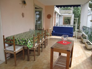 A patio with a dining table, chairs, and a blue sofa.