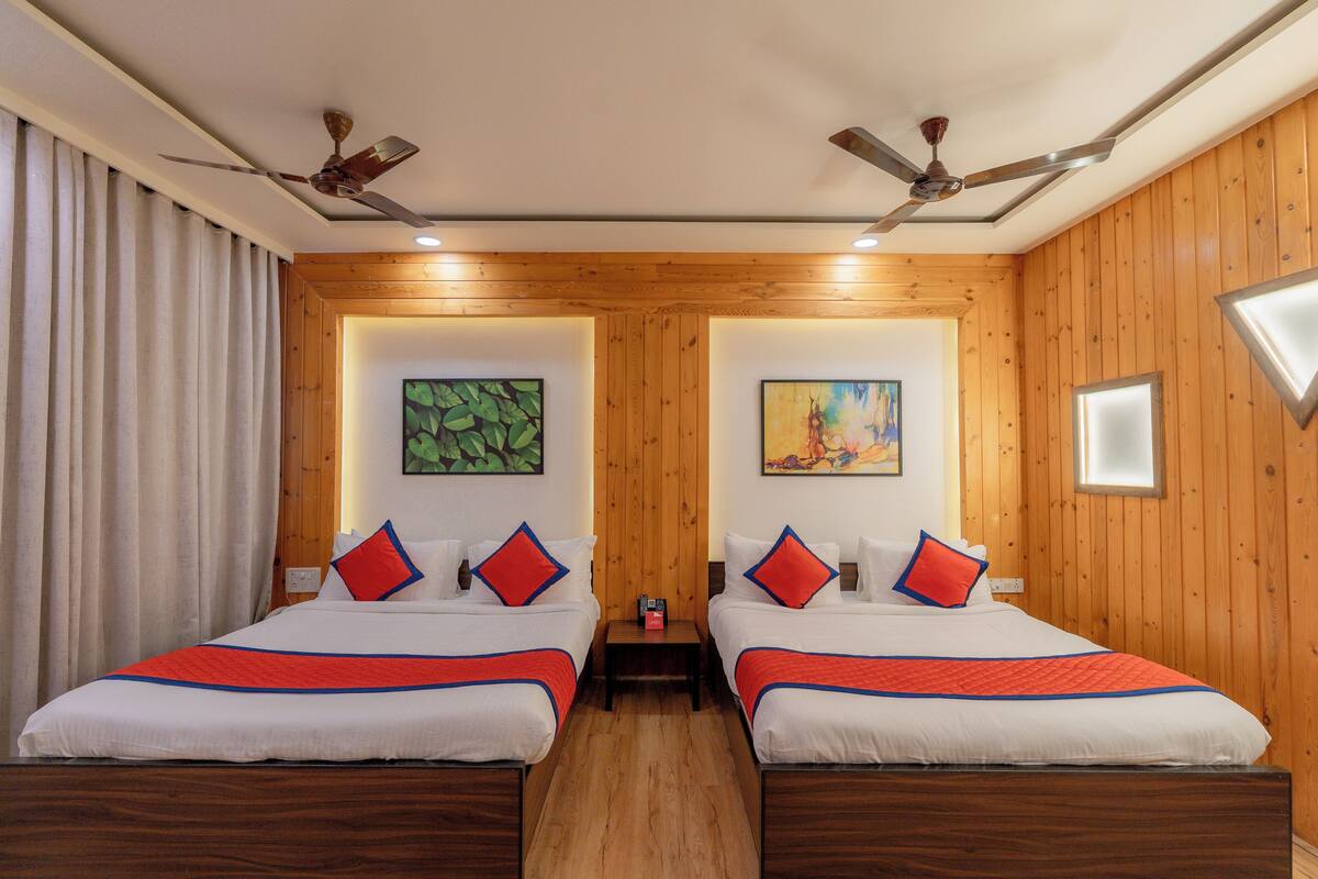 A hotel room with two beds, wooden paneling, ceiling fans, and artwork on the walls.