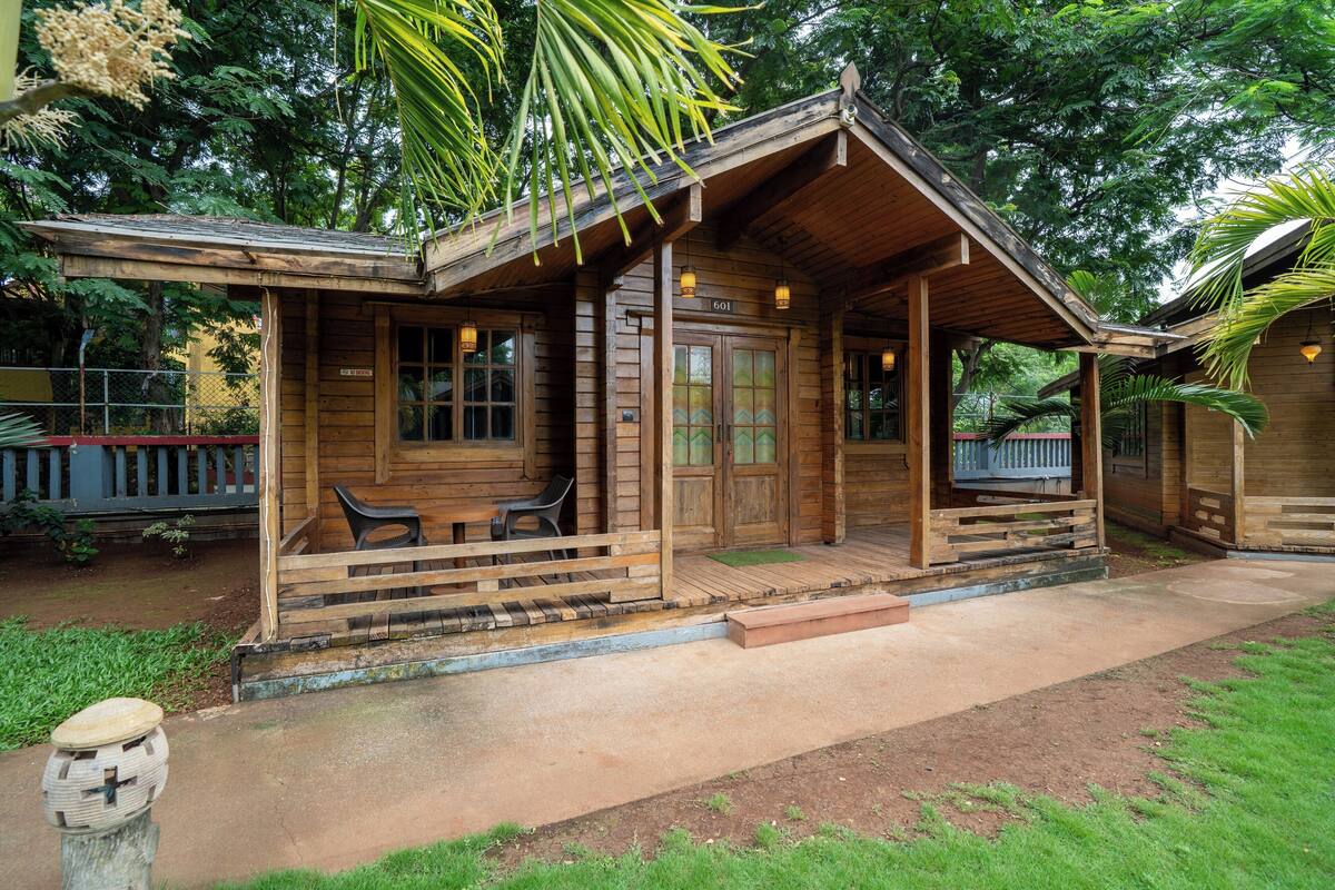A wooden cabin with a porch, a covered seating area, and a number '601' sign.