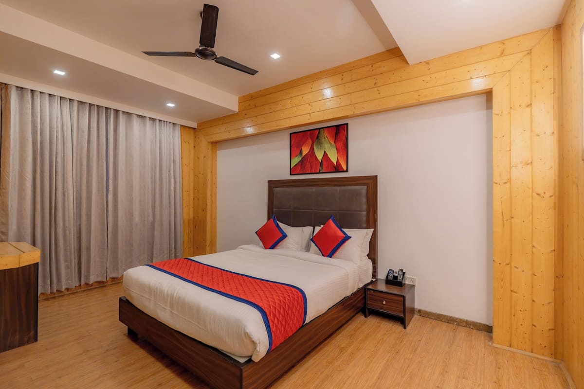 A bedroom with a wooden headboard, a bed with red and blue pillows, a nightstand, and a ceiling fan.