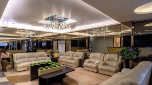 Eine großzügige Lobby mit Ledersofas, einem zentralen Couchtisch und einer modernen Deckenleuchte.