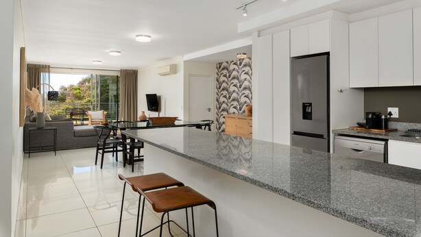 A modern kitchen with a large island, white cabinetry, and stainless steel appliances. - The Odyssey 302 (Cape Town)