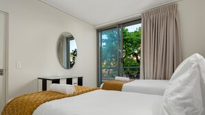 A hotel room with two beds, a large window with curtains, a mirror, and a small table with a towel. - The Odyssey 302 (Cape Town)