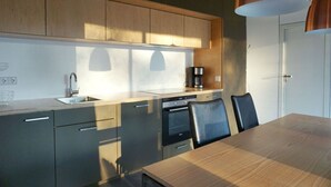 A modern kitchen with a wooden countertop, stainless steel appliances, and a dining area with a wooden table and chairs. - Design Ferienwohnung Nienrausch Apartment 1 (Timmendorfer Strand)