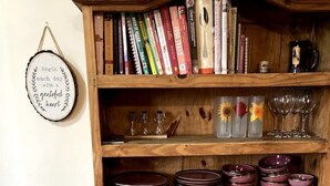 A wooden cabinet with books, glassware, and plates. - Pilgrims Rest - Cheddar Guest House with Annexe (Cheddar)