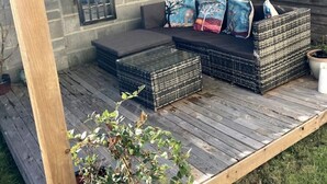 A wooden deck with a built-in seating area, a stone wall, and a window. - Pilgrims Rest - Cheddar Guest House with Annexe (Cheddar)