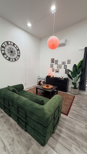 A living room with a green sofa, a coffee table, a red lantern, and a wall decorated with framed pictures.