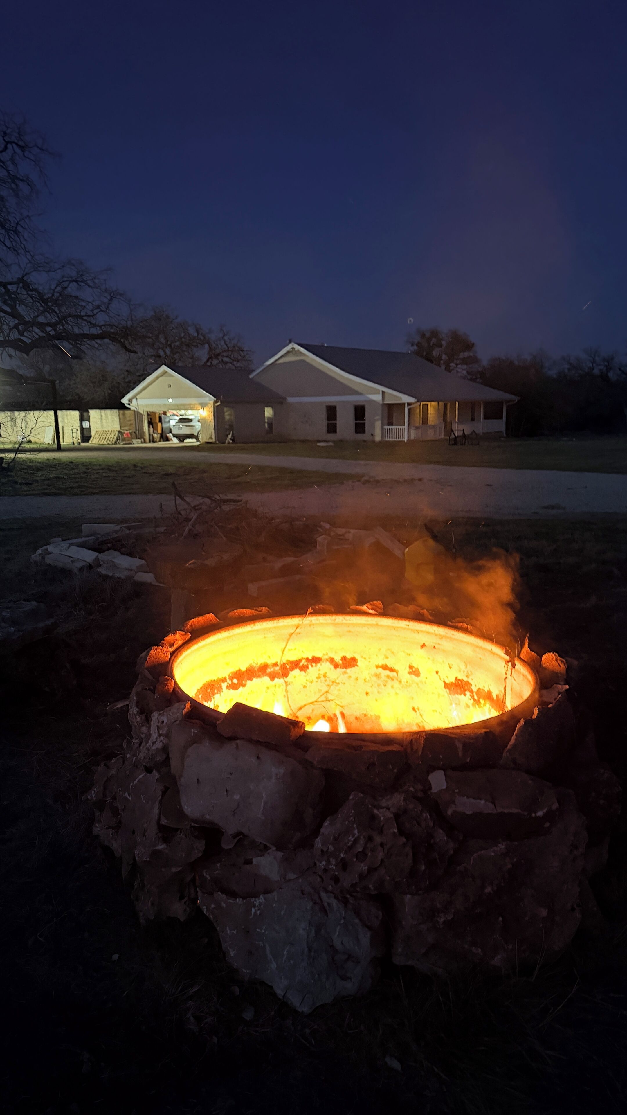 A fire pit with a house in the background.