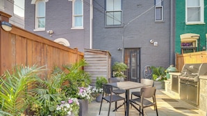 A backyard with a wooden fence, a barbecue grill, and a dining area with chairs and a table. - 2 Mi to National Mall: Stunning Townhome w/ Patio! (Washington)