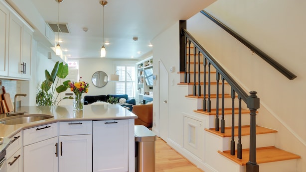 A modern kitchen with white cabinets, a central island, and a stainless steel sink. - 2 Mi to National Mall: Stunning Townhome w/ Patio! (Washington)