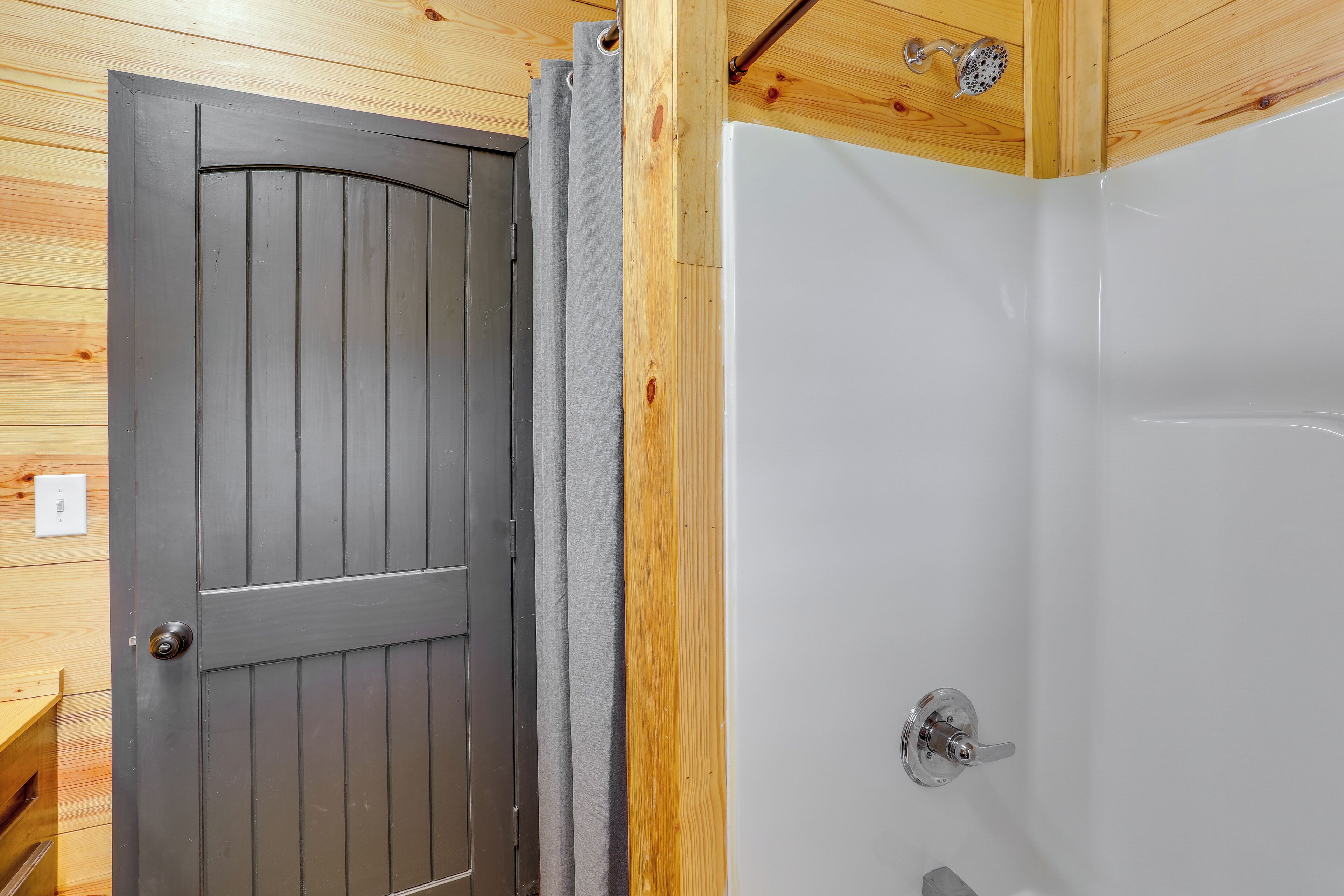 Una puerta de madera con un picaporte moderno y un box de ducha blanco con un grifo cromado.