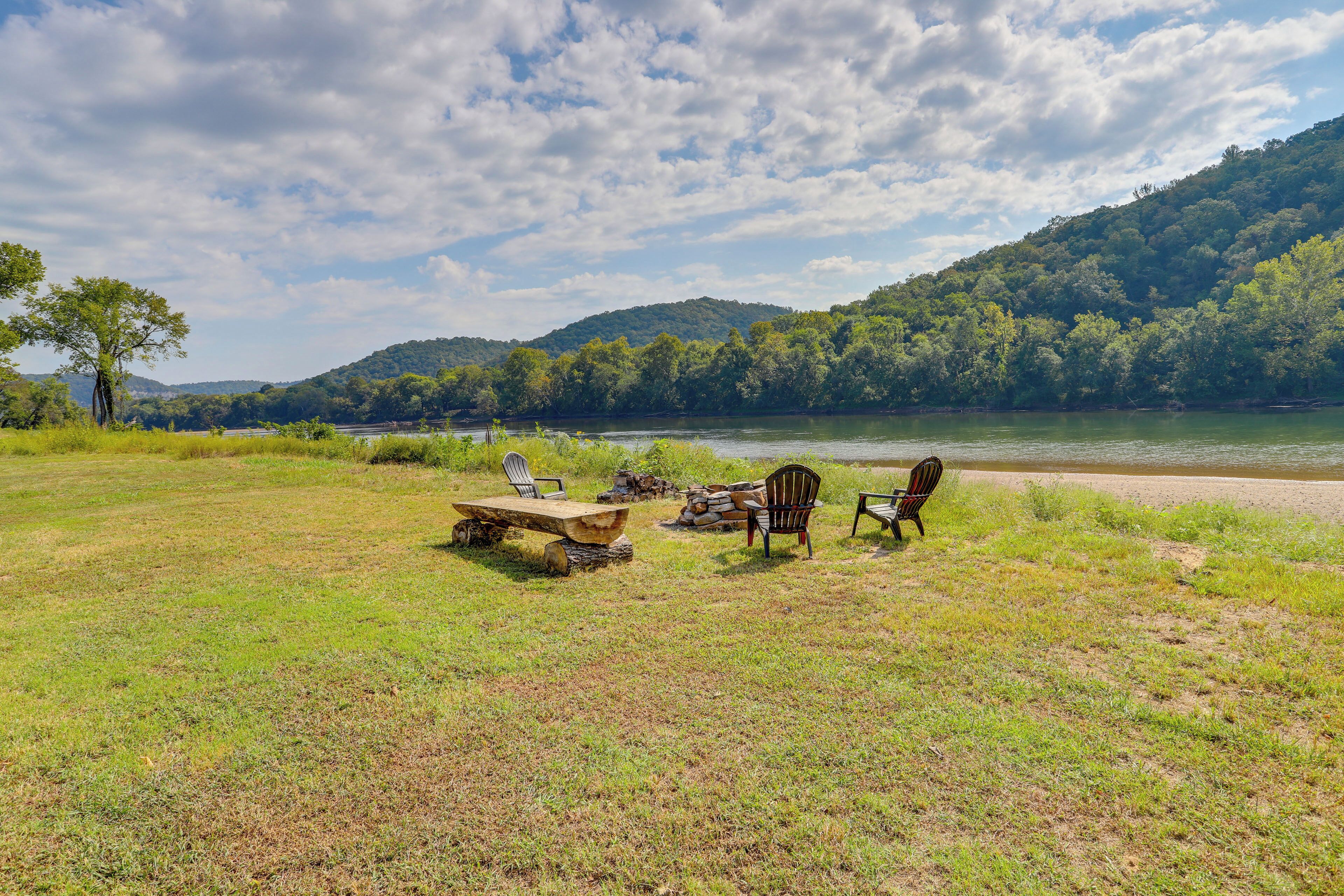 Un camping junto al lago con una mesa de picnic, dos sillas Adirondack y un brasero.