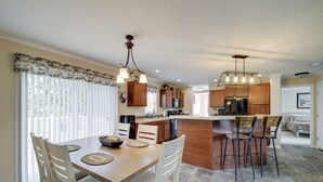 A modern kitchen with wooden cabinets, a central island, and bar stools. - Efficiently Equipped Lewis Home: Deck & Gas Grill! (Lewis)