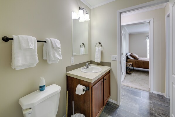 A bathroom with a toilet, sink, and mirror. There are towels hanging on a rack. - Efficiently Equipped Lewis Home: Deck & Gas Grill! (Lewis)
