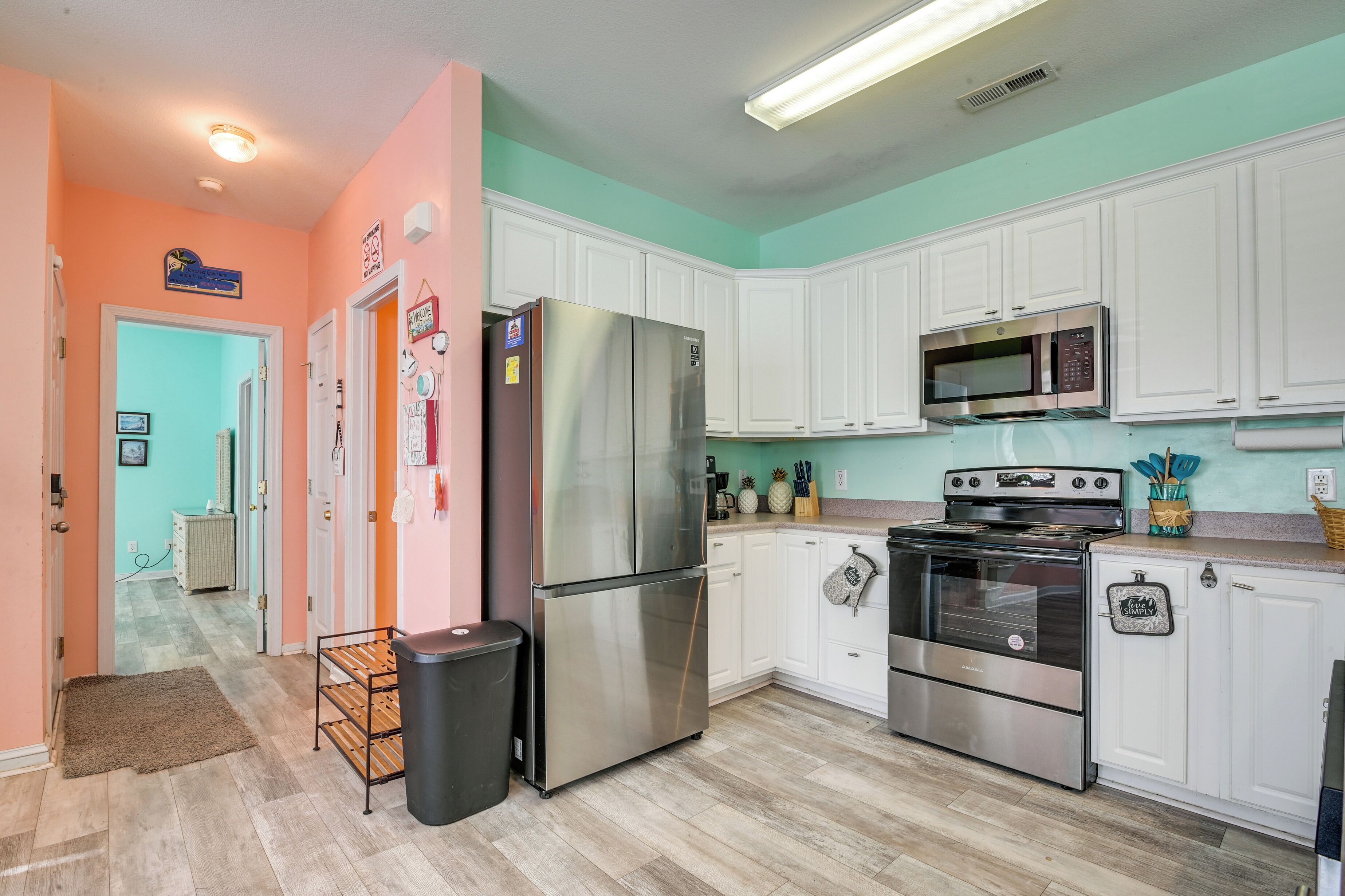 Une cuisine avec des armoires blanches, des appareils en acier inoxydable et un mur d’accent de couleur turquoise.