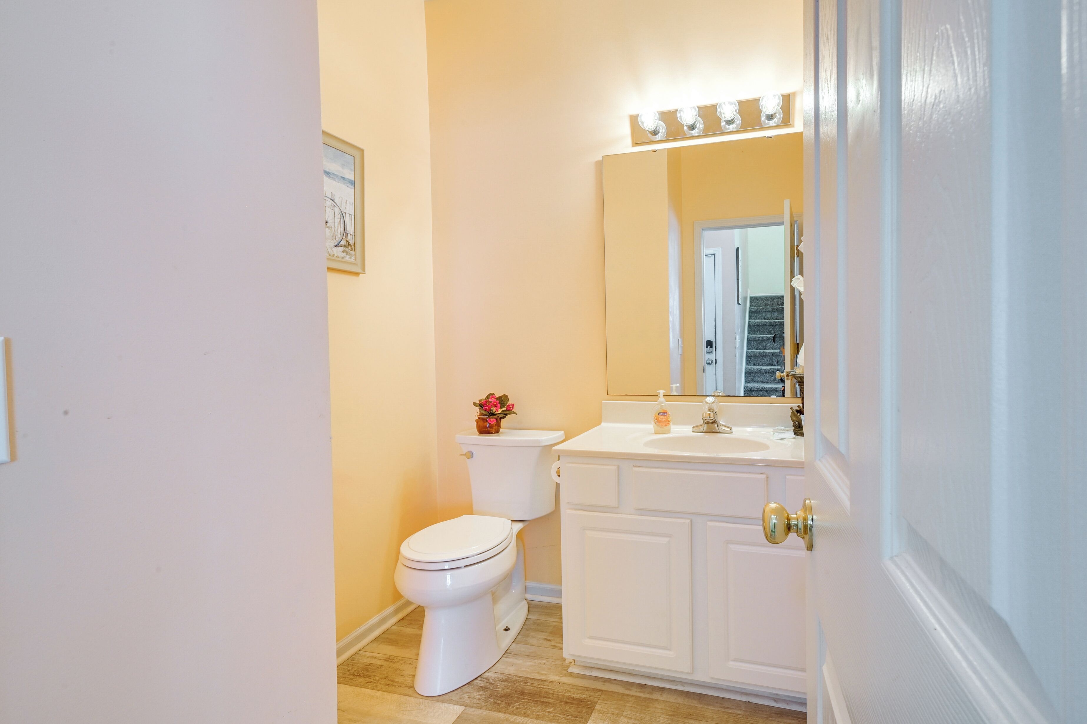 A bathroom with a white toilet, a sink with a mirror above it, and a door with a light switch.