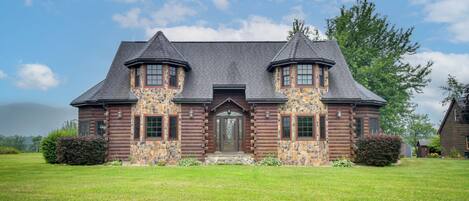 A log cabin with a stone facade, two towers, and a front door.