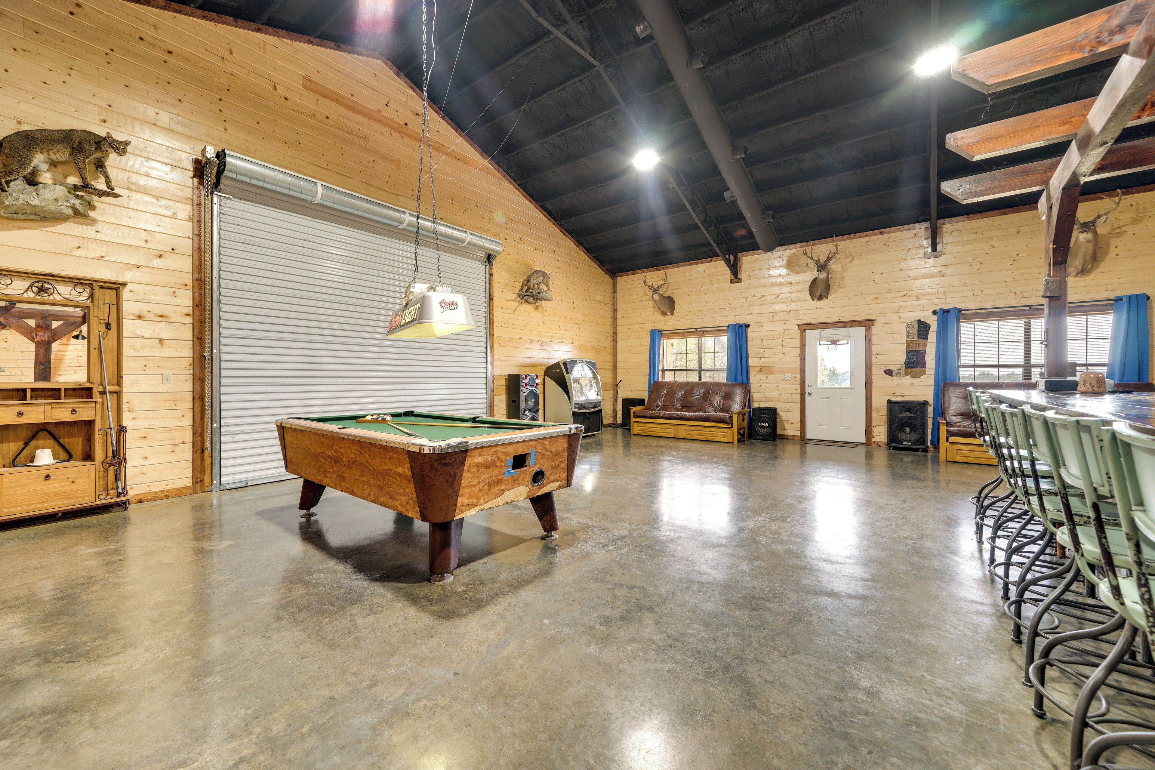 A spacious indoor area with a pool table, wooden walls, and mounted animal heads.