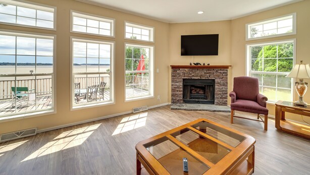 Un salón amplio con ventanas grandes, chimenea y vistas al exterior.