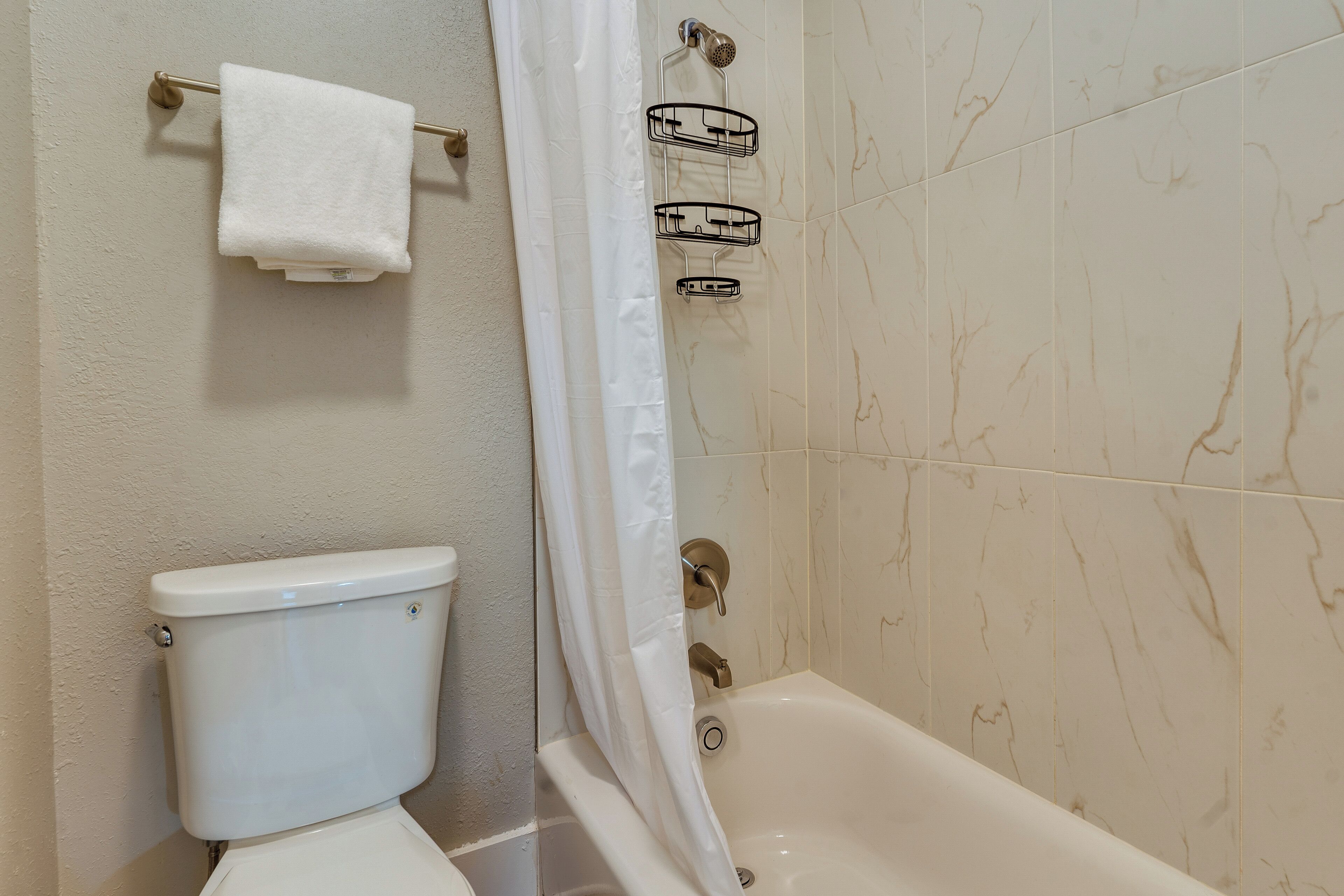A bathroom with a toilet, a bathtub, and a shower curtain.