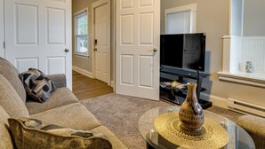 A living room with a sofa, a coffee table, a television, and a door leading to another room. - Spokane Vacation Rental w/ Central Location! (Spokane)