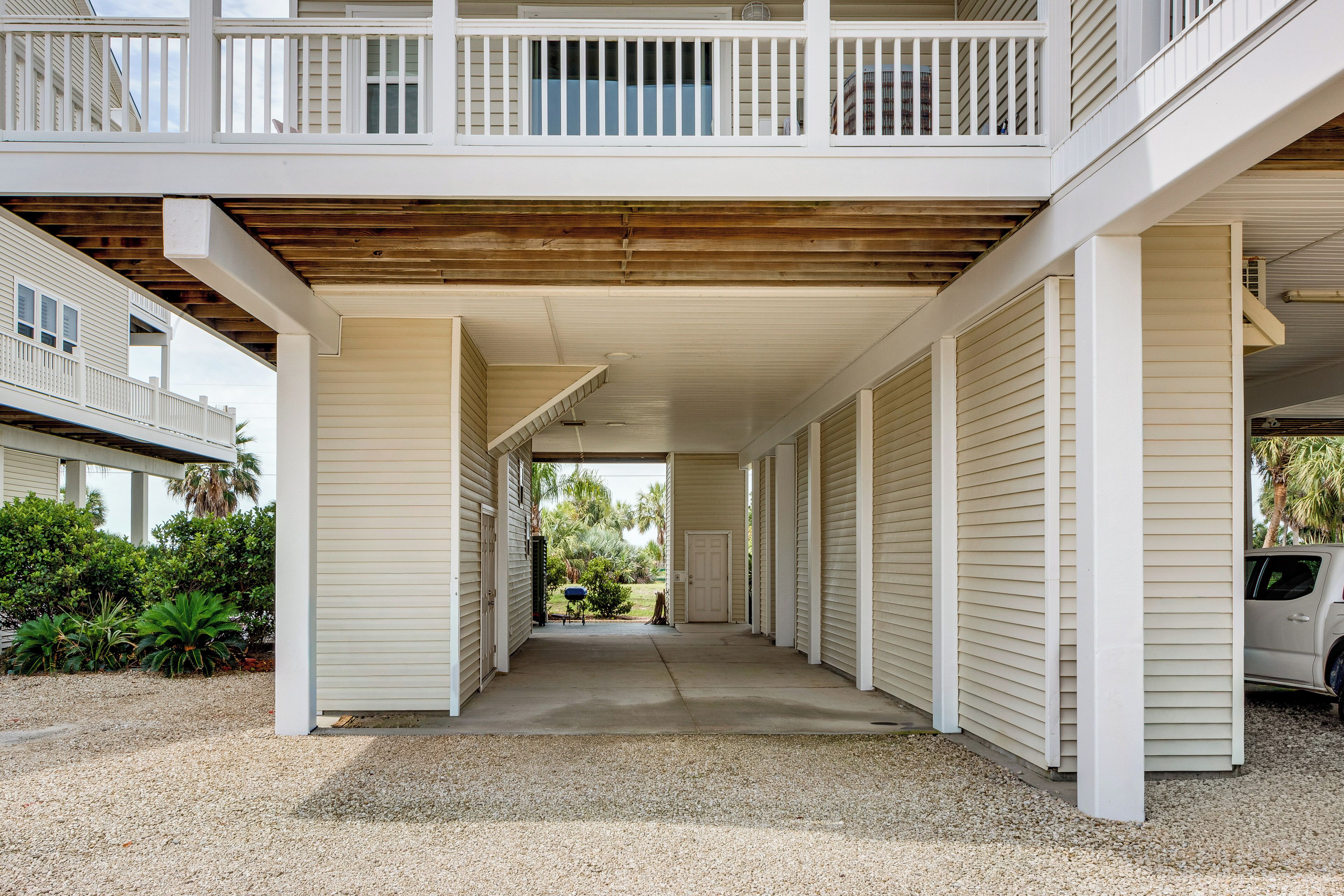 A covered outdoor area with a concrete floor, white siding, and a wooden ceiling.