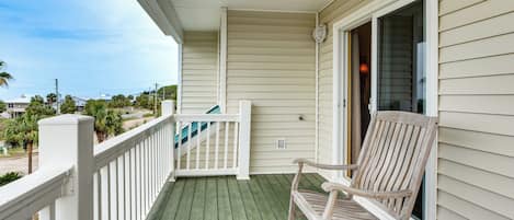 A wooden porch with a rocking chair and a white railing.