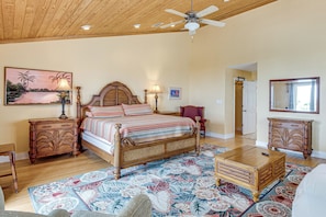 A bedroom with a bed, nightstands, a dresser, a ceiling fan, and a floral rug.