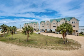 A beachfront hotel with multiple buildings, a sandy area, and palm trees.