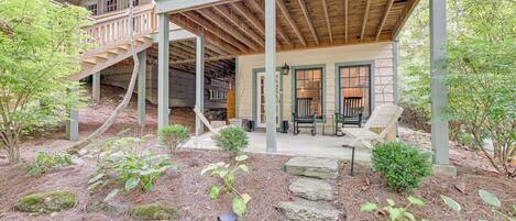 A rustic cabin with a wooden deck, stone steps, and a small porch area.