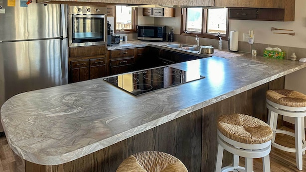 Una cocina moderna con una isla grande, electrodomésticos de acero inoxidable y muebles de madera.