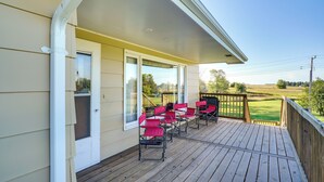 Una terraza de madera con sillas rojas y vista a un campo de golf.