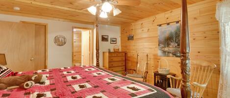 A cozy wooden cabin bedroom with a four-poster bed, a ceiling fan, and a rustic decor.