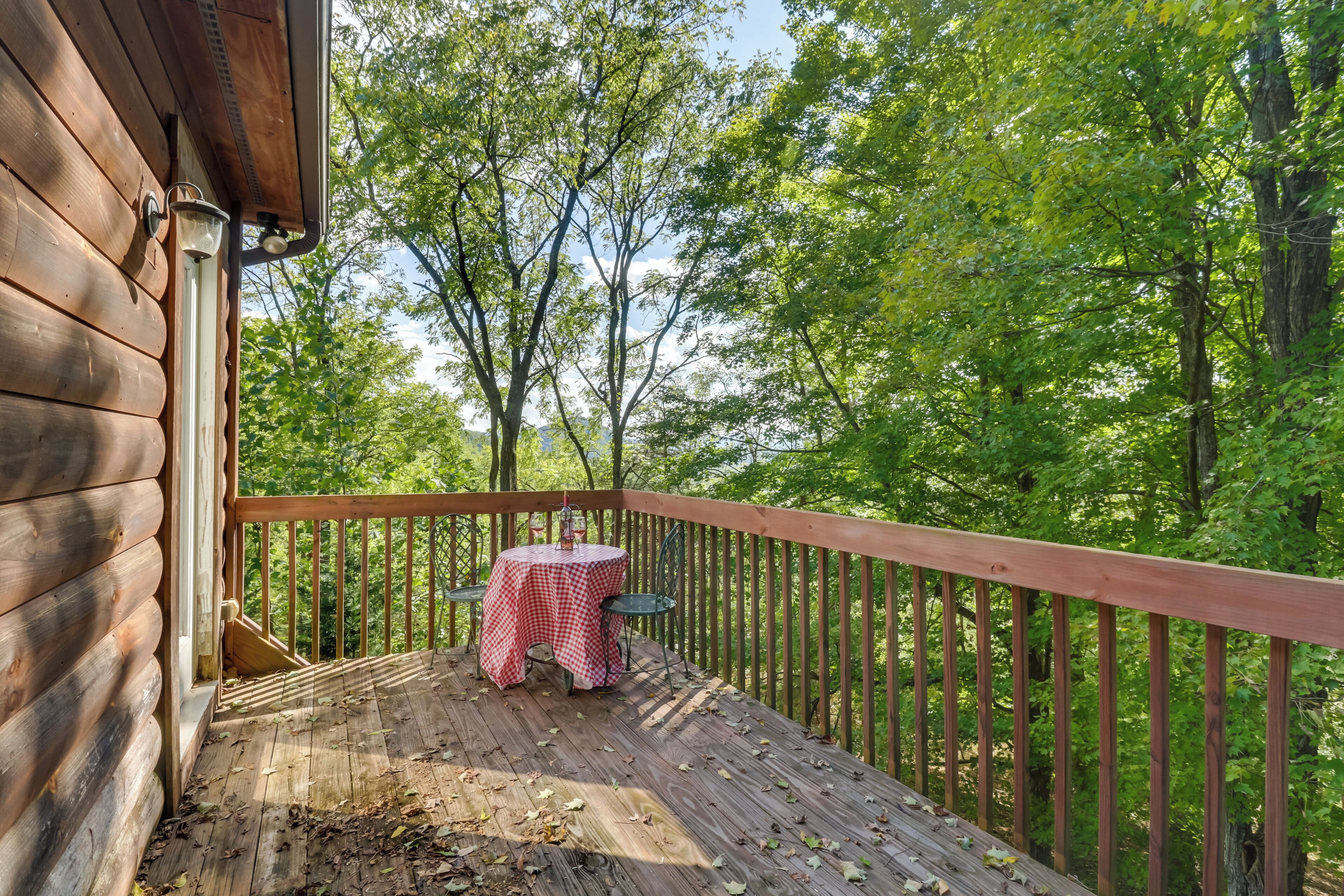 A wooden deck with a table and chairs, surrounded by trees.