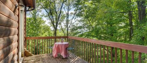 A wooden deck with a table and chairs, surrounded by trees.