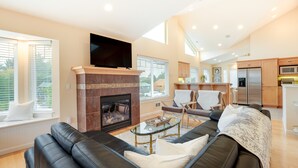 Una sala moderna con chimenea, sofás de cuero y un televisor de pantalla plana.