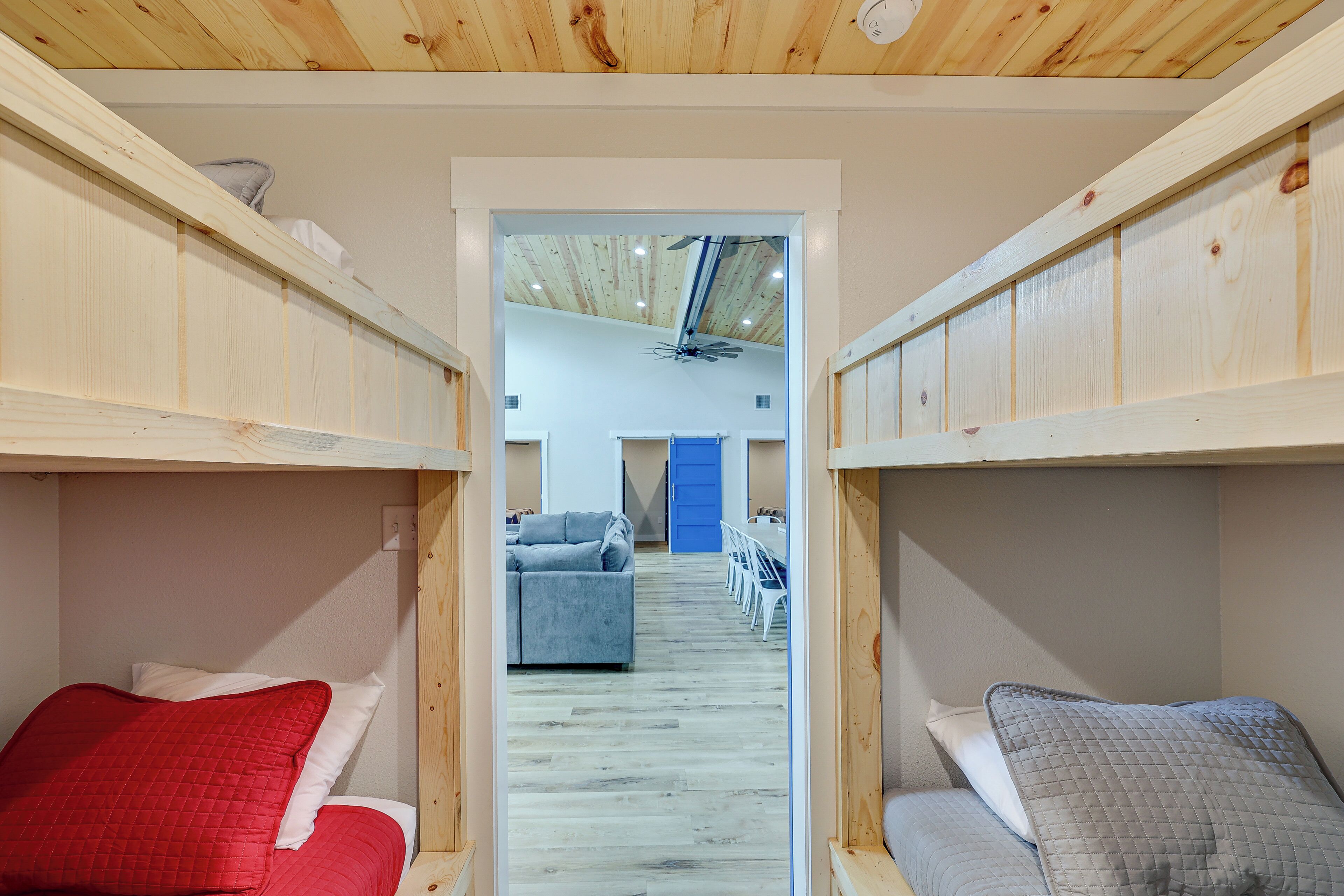 Un couloir étroit, avec des lits superposés de chaque côté, qui mène à un espace de vie comprenant un canapé et des fauteuils.