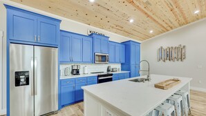 A modern kitchen with blue cabinets, stainless steel appliances, and a white island. - Riverfront 'caddo Shack' Home w/ Views & Fire Pit (Glenwood)