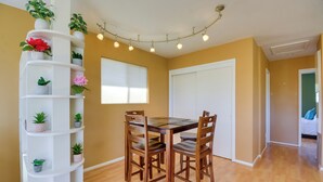A dining area with a wooden table and chairs, surrounded by a white shelving unit with potted plants. - 1 Mi to Whiskey Row: Home w/ Fire Pit & Deck (Prescott)