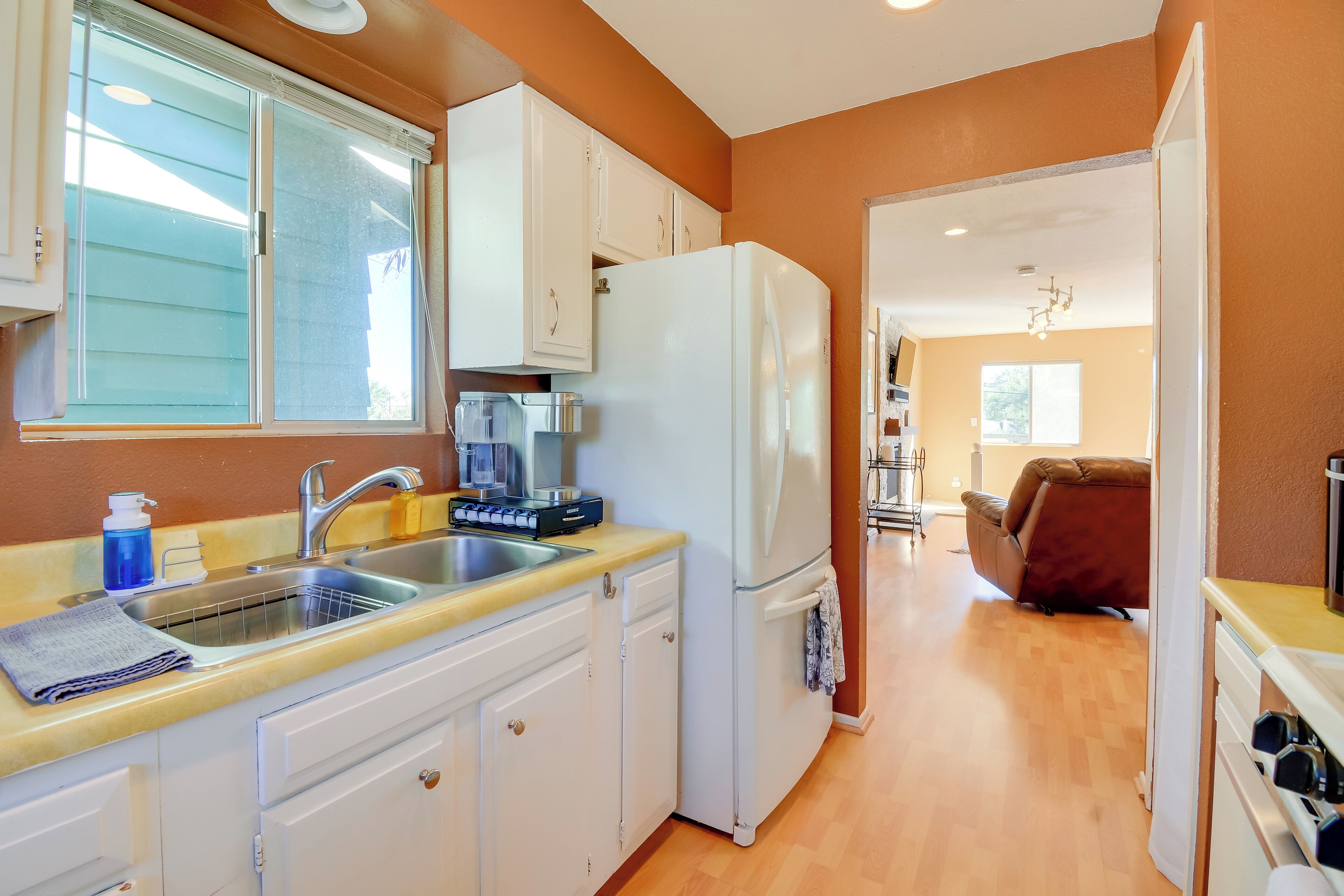A kitchen with white cabinets, a stainless steel sink, and a refrigerator.