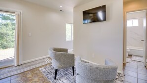 A spacious room with two grey armchairs, a large flat-screen TV mounted on the wall, and a sliding glass door leading to an outdoor area. - 1 Mi to Whiskey Row: Home w/ Fire Pit & Deck (Prescott)