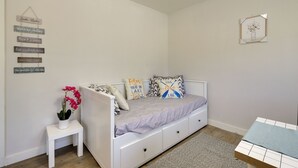 A bedroom with a white bed, a small white nightstand, a vase with flowers, and motivational wall art. - Quiet Lakefront Clearlake Vacation Rental! (Clearlake)