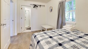 A bedroom with a bed, a bedside table, a coat rack, and a window with curtains. - Quiet Lakefront Clearlake Vacation Rental! (Clearlake)