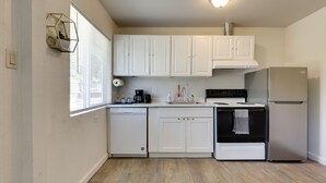 A modern kitchen with white cabinets, a dishwasher, a stove, and a refrigerator. - Quiet Lakefront Clearlake Vacation Rental! (Clearlake)